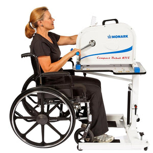HCI Hydraulic UBE Table|Adjustable Arm adjusts height from 27"-37 and hydraulic pump|Turn knob allows user to lock casters in place to keep table more sturdy|Height adjustment allows for a variety of users to enjoy use of table|User with the HCI Hydraulic UBE Table and the Monark Ergometer