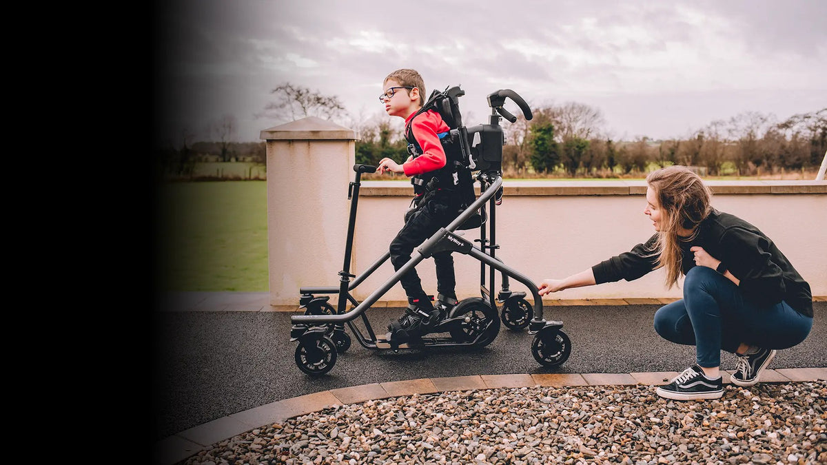 Child using Leckey MyWay+ gait trainer outdoors with caregiver